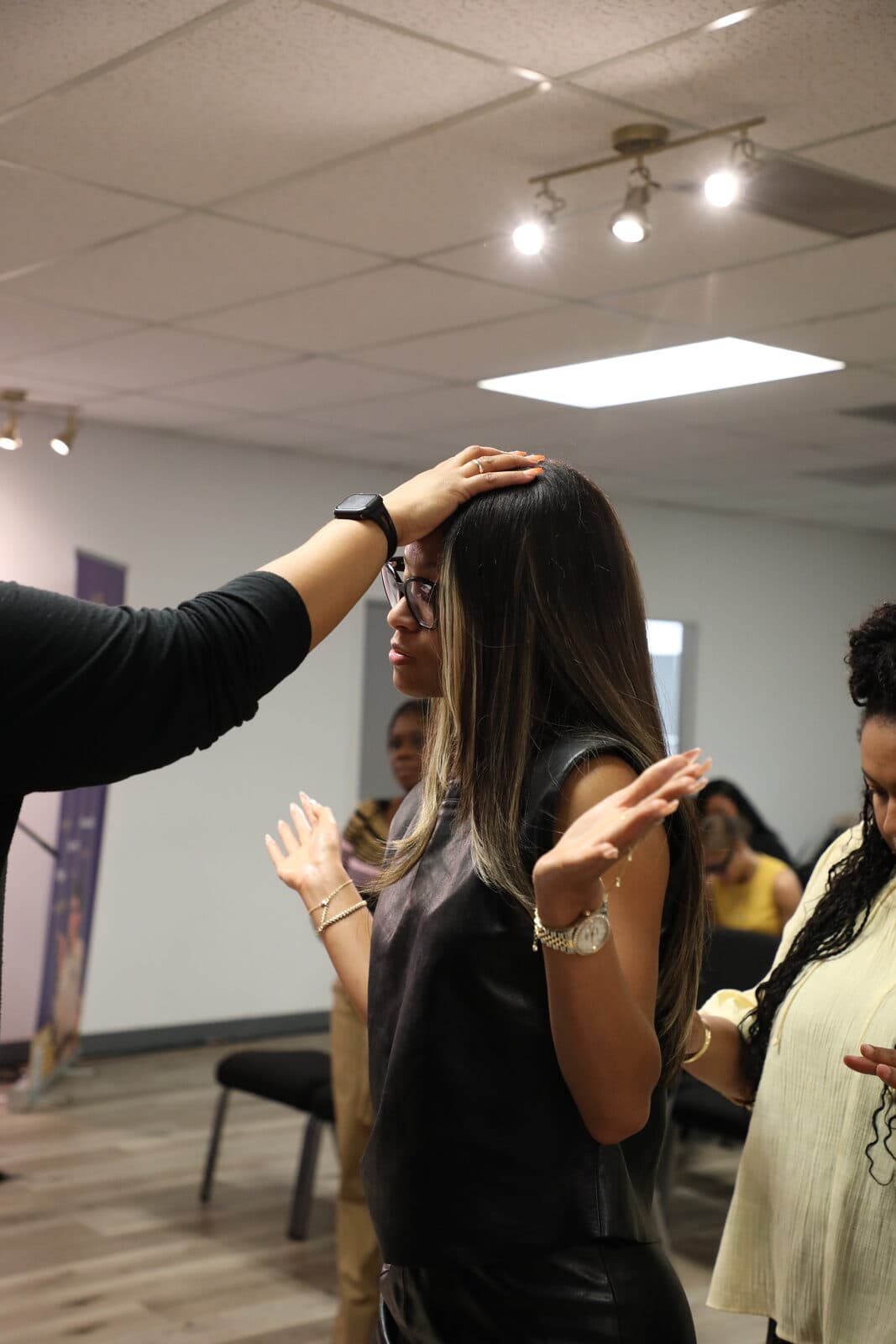 A hand laid in prayer on a woman’s head during ministry time