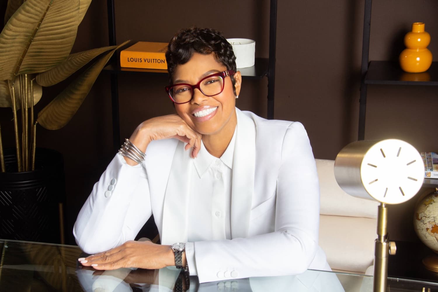 Pastor Yorie Gipson at her desk in a white suit, smiling